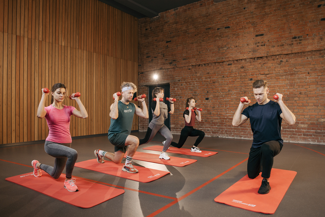 Group of People Exercising with Dumbbells on a Yoga Mat
